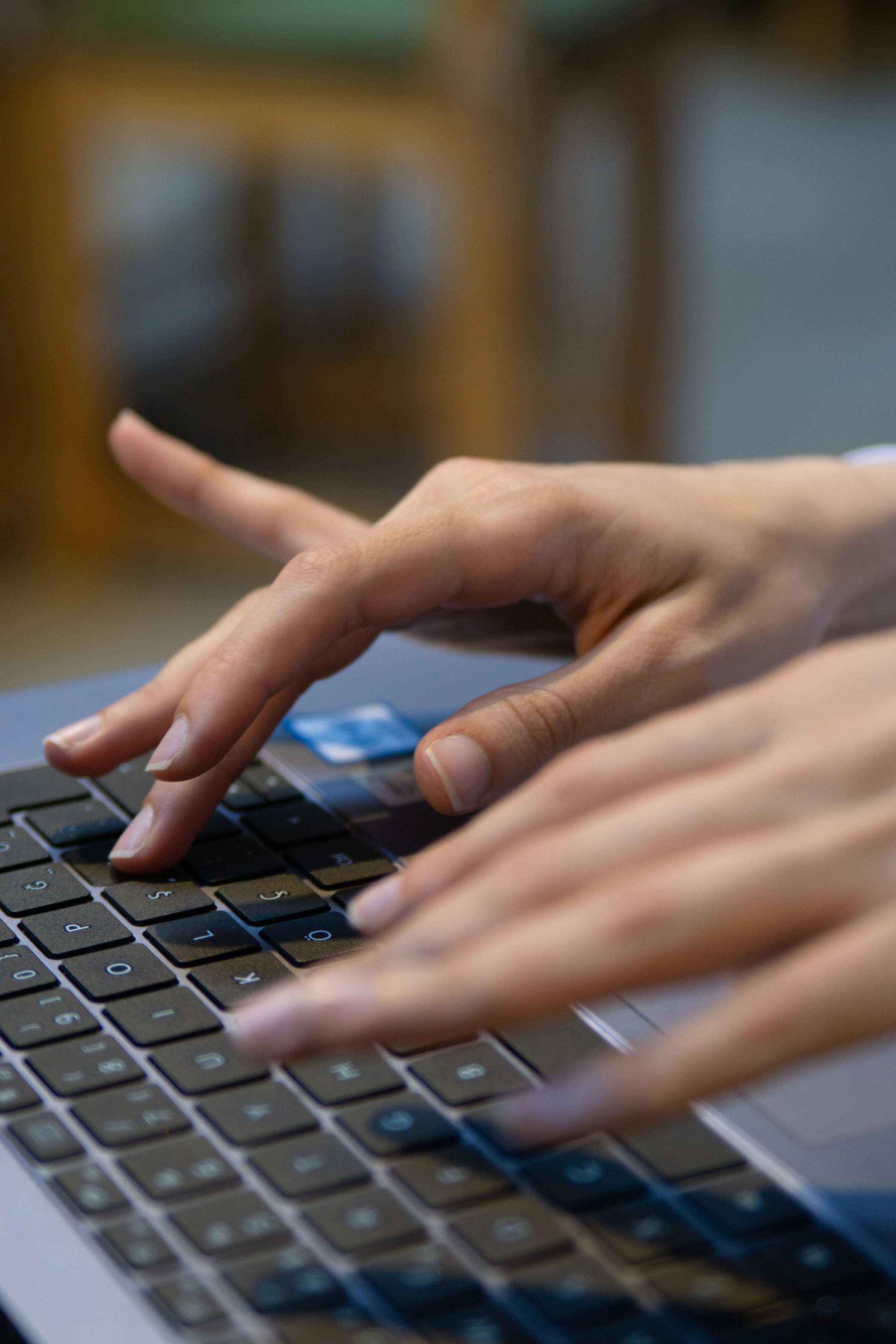 Hände an Tastatur vor einem Bildschirm mit Tabellendaten und Monitor